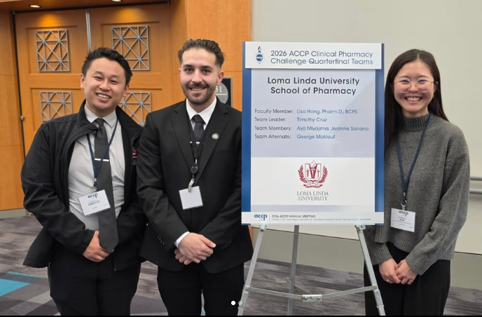 Three Students pose in front of the quarterfinal team challenge poster