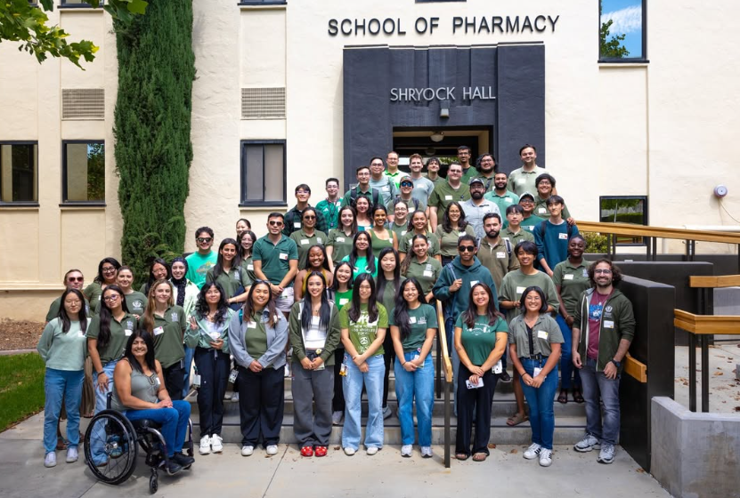 first year pharmacy students wearing matching green school shirts on the steps outside of Shryock Hall