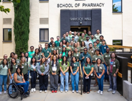first year pharmacy students wearing matching green school shirts on the steps outside of Shryock Hall